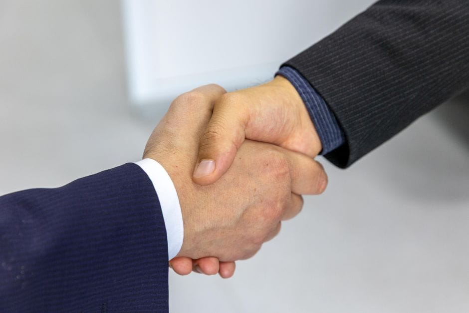 Gros plan de deux hommes d'affaires se serrant la main, symbolisant l'accord et le partenariat.