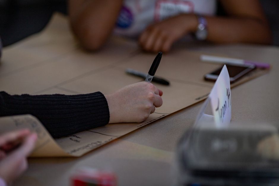 Des mains écrivant sur un grand papier lors d'une réunion d'équipe collaborative, mettant en avant la planification et la stratégie.