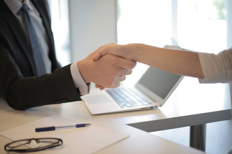 Gros plan sur une poignée de main professionnelle au-dessus d'un ordinateur portable lors d'une réunion d'affaires dans un bureau.