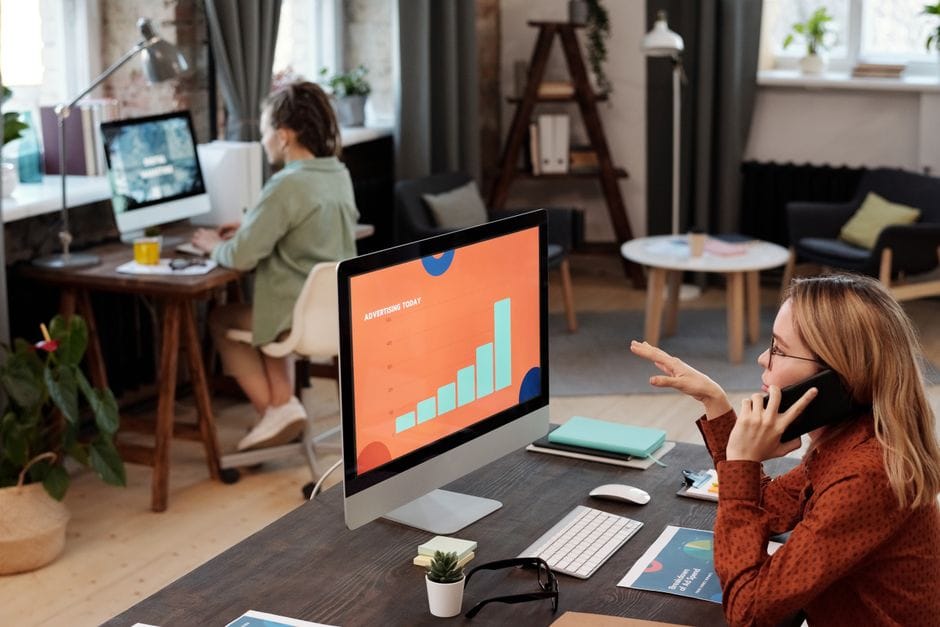 Deux professionnels engagés dans leur travail avec des ordinateurs et un téléphone dans un cadre de bureau moderne.