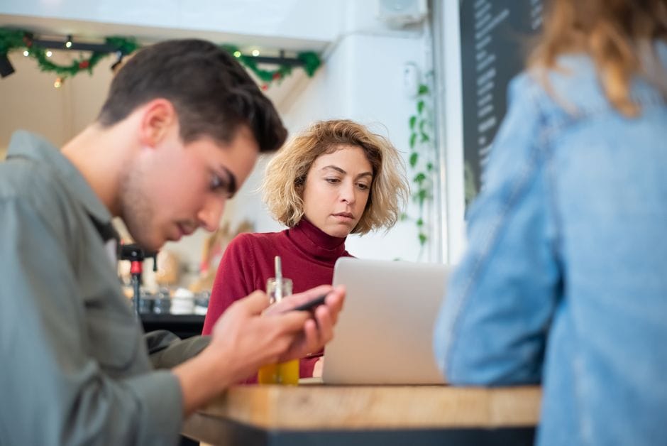 Jeunes professionnels collaborant dans un café, travaillant sur des ordinateurs portables et discutant d'idées.