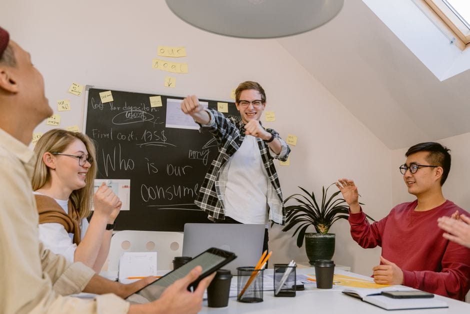 Jeunes professionnels dans un bureau dynamique célébrant le succès de l'équipe avec des sourires et de l'enthousiasme.