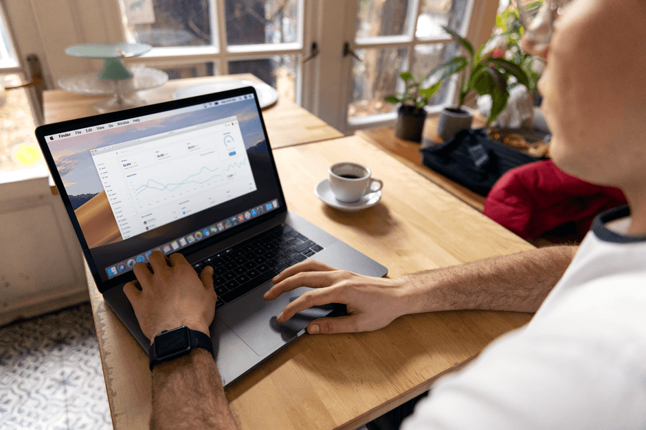 Une personne travaillant sur un ordinateur portable avec des analyses commerciales affichées, montrant une configuration de télétravail dans un environnement confortable.