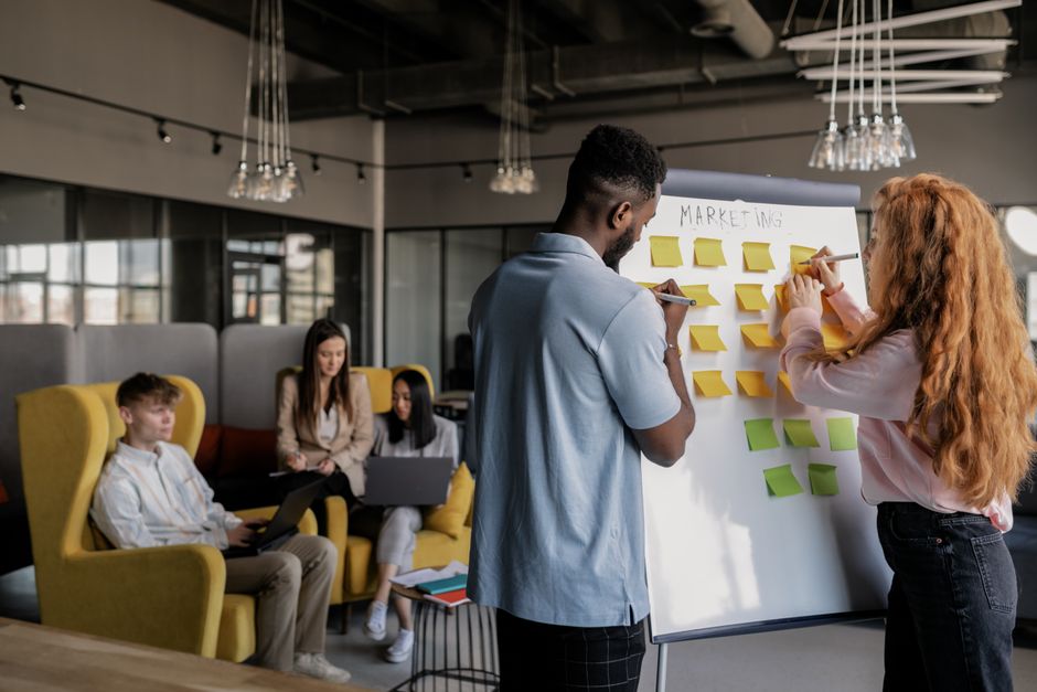 Équipe collaborant dans un bureau moderne, planifiant une stratégie sur un tableau blanc, jeunes adultes travaillant ensemble.