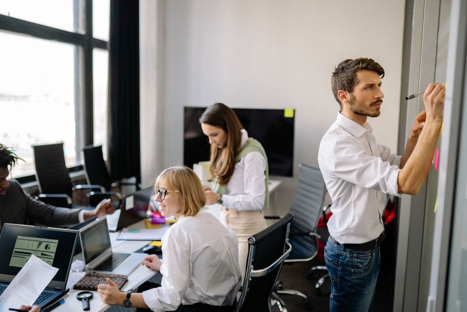 Un groupe diversifié de collègues collaborant dans un bureau moderne, échangeant des idées et planifiant.