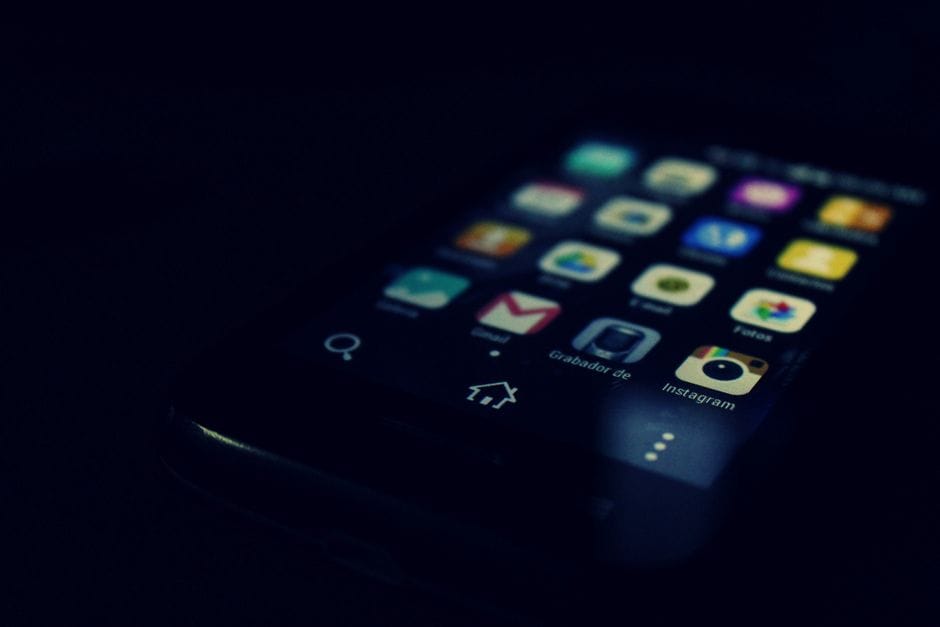 Gros plan sur un écran de smartphone à thème sombre mettant en avant diverses applications et la technologie tactile.